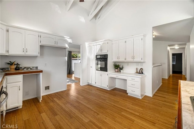 1720 N Cherry St, Chico, CA 95926 - kitchen featuring oven, white cabinetry, light wood finished floors, a towering ceiling, and light countertops