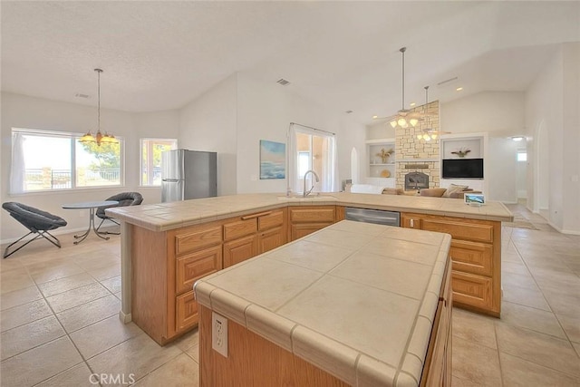 8250 Snow Cap Ave, Pinon Hills, CA 92372 - kitchen featuring appliances with stainless steel finishes, a kitchen island, tile counters, vaulted ceiling, and a fireplace