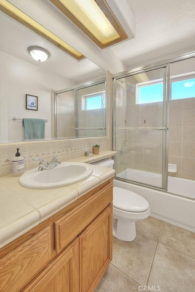 8250 Snow Cap Ave, Pinon Hills, CA 92372 - bathroom featuring vanity, tile patterned flooring, bath / shower combo with glass door, and toilet