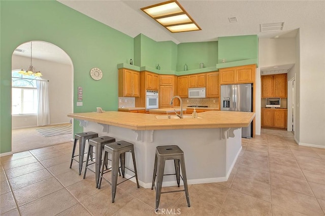 8250 Snow Cap Ave, Pinon Hills, CA 92372 - kitchen featuring stainless steel appliances, a sink, high vaulted ceiling, light tile patterned floors, and a breakfast bar area
