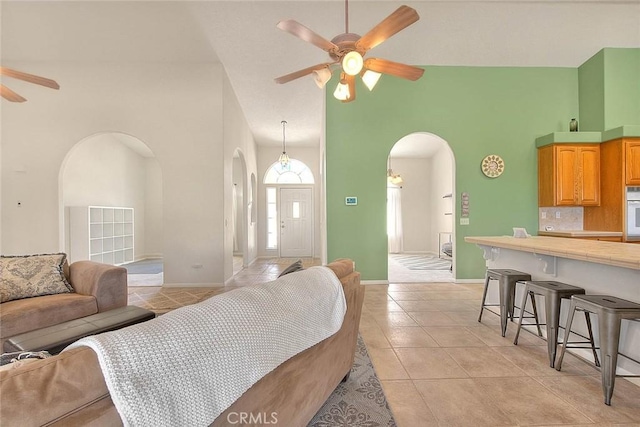 8250 Snow Cap Ave, Pinon Hills, CA 92372 - living room with arched walkways, ceiling fan, high vaulted ceiling, light tile patterned floors, and baseboards
