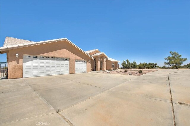 8250 Snow Cap Ave, Pinon Hills, CA 92372 - view of front facade featuring concrete driveway, an attached garage, and stucco siding