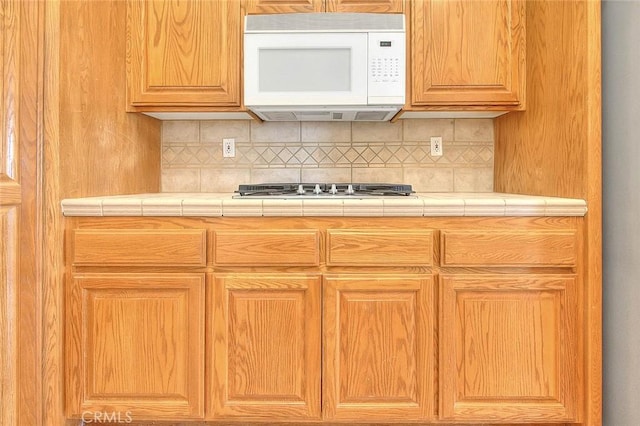 8250 Snow Cap Ave, Pinon Hills, CA 92372 - kitchen with white microwave, backsplash, tile countertops, and stainless steel gas stovetop