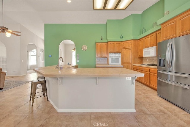 8250 Snow Cap Ave, Pinon Hills, CA 92372 - kitchen with white appliances, arched walkways, tile countertops, light tile patterned flooring, and a high ceiling