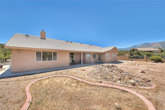 8250 Snow Cap Ave, Pinon Hills, CA 92372 - rear view of house featuring a tiled roof, a patio area, stucco siding, a chimney, and a mountain view