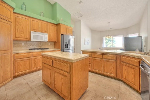 8250 Snow Cap Ave, Pinon Hills, CA 92372 - kitchen with stainless steel appliances, tile counters, backsplash, light tile patterned floors, and a textured ceiling