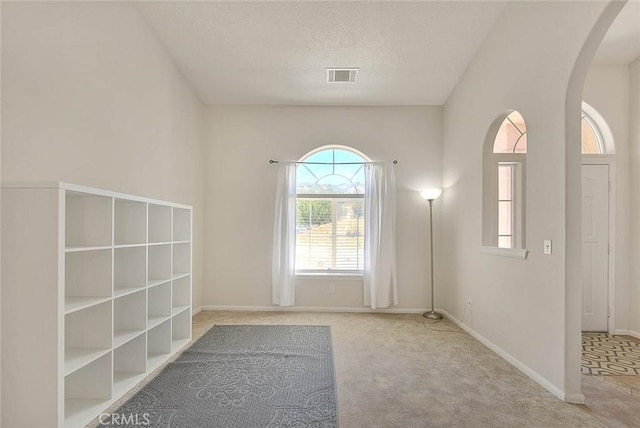 8250 Snow Cap Ave, Pinon Hills, CA 92372 - unfurnished room featuring arched walkways, carpet floors, a textured ceiling, and baseboards