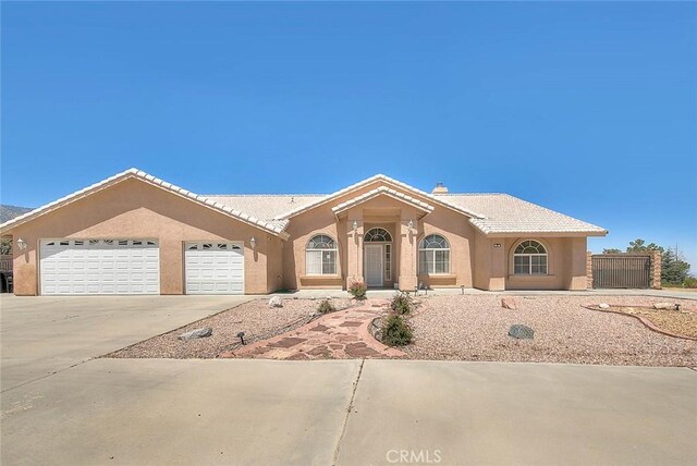 8250 Snow Cap Ave, Pinon Hills, CA 92372 - view of front facade with driveway, an attached garage, and stucco siding