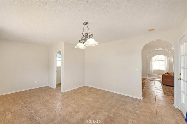 8250 Snow Cap Ave, Pinon Hills, CA 92372 - empty room with arched walkways, a textured ceiling, light tile patterned flooring, and baseboards
