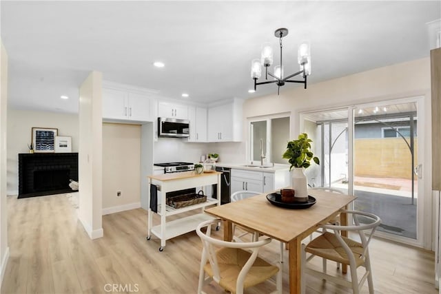 1024 E Dore St, West Covina, CA 91792 - kitchen with stainless steel microwave, a chandelier, white cabinets, light wood-style floors, and a brick fireplace
