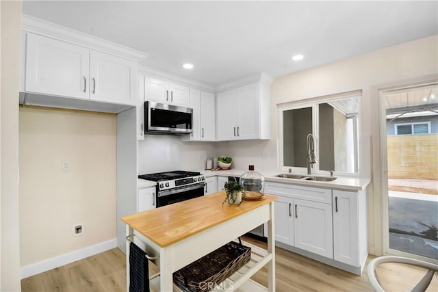 1024 E Dore St, West Covina, CA 91792 - kitchen with appliances with stainless steel finishes, a sink, white cabinets, light wood-style flooring, and recessed lighting