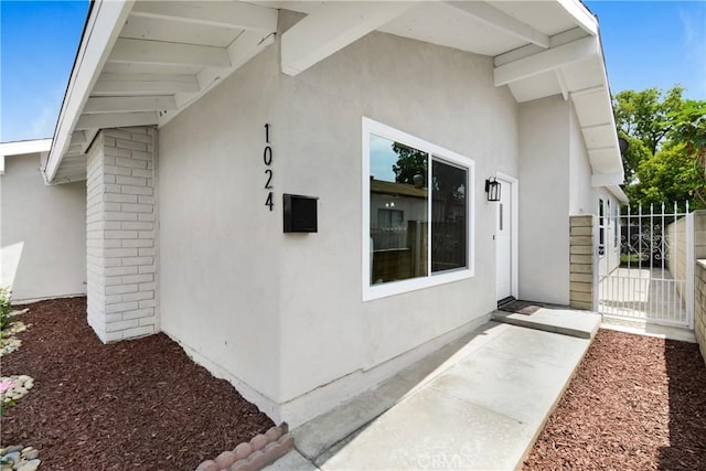 1024 E Dore St, West Covina, CA 91792 - view of exterior entry with stucco siding, a gate, and brick siding