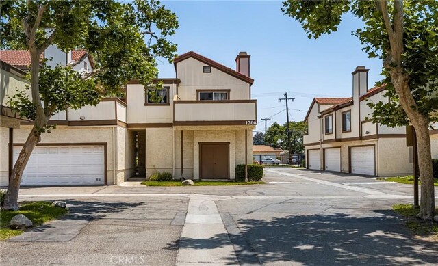 1206 S Cypress Ave Unit F, Ontario, CA 91762 - view of front of house with a garage, concrete driveway, a chimney, stucco siding, and a balcony