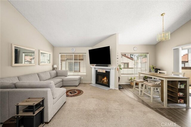 1206 S Cypress Ave Unit F, Ontario, CA 91762 - living room featuring vaulted ceiling, a fireplace with flush hearth, a chandelier, a textured ceiling, and baseboards