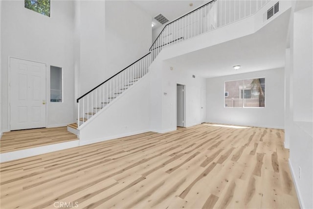 7522 Calais Ct, Rancho Cucamonga, CA 91730 - unfurnished living room with a high ceiling, stairway, wood finished floors, healthy amount of natural light, and baseboards