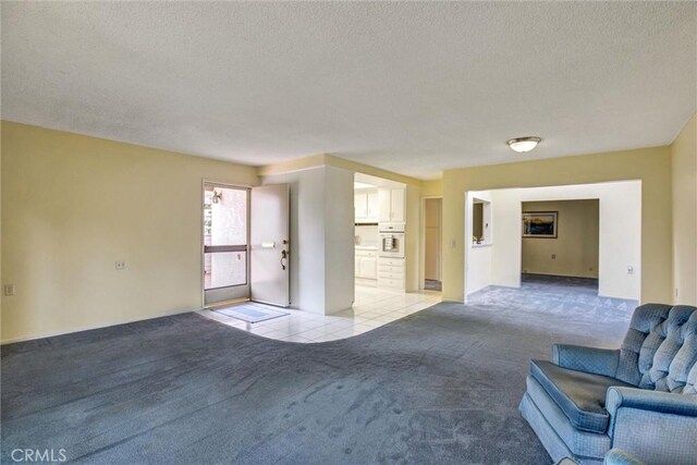 2160 Via Mariposa E Unit D, Laguna Woods, CA 92637 - unfurnished living room with light carpet, a textured ceiling, and light tile patterned floors