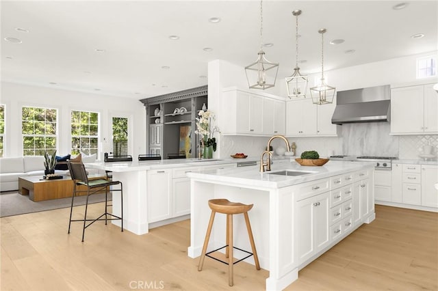 3 Seabluff, Newport Beach, CA 92660 - kitchen featuring wall chimney exhaust hood, stainless steel gas cooktop, open floor plan, light wood-style floors, and decorative backsplash