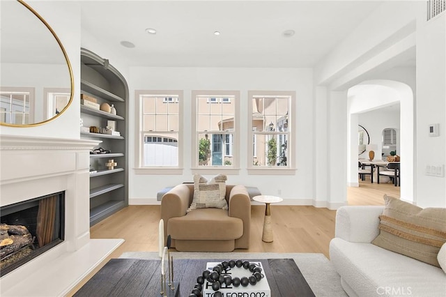 3 Seabluff, Newport Beach, CA 92660 - living area with light wood-type flooring, a fireplace with raised hearth, arched walkways, and recessed lighting