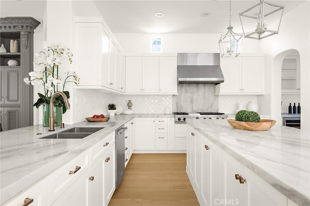 3 Seabluff, Newport Beach, CA 92660 - kitchen featuring wall chimney range hood, appliances with stainless steel finishes, light stone countertops, white cabinetry, and decorative backsplash