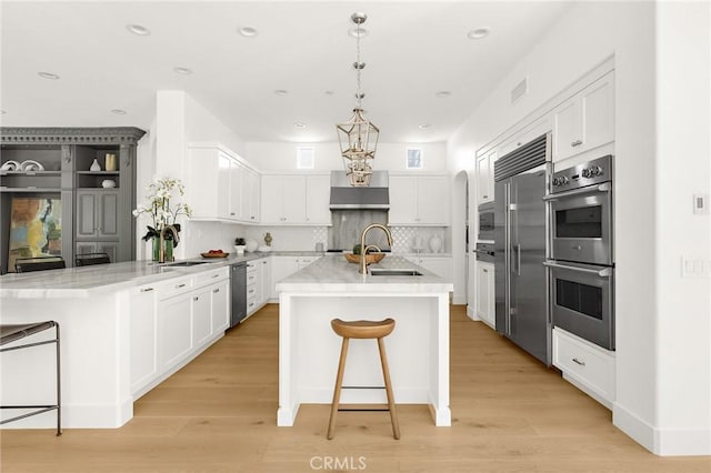 3 Seabluff, Newport Beach, CA 92660 - kitchen with appliances with stainless steel finishes, a peninsula, white cabinetry, light wood finished floors, and recessed lighting
