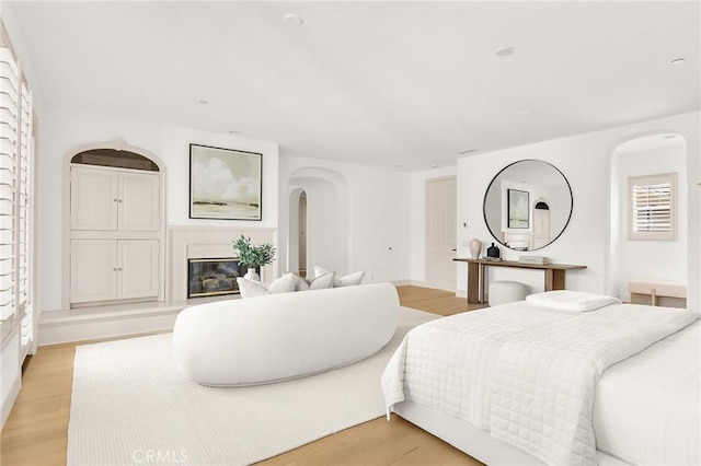3 Seabluff, Newport Beach, CA 92660 - bedroom featuring arched walkways, a glass covered fireplace, and light wood finished floors