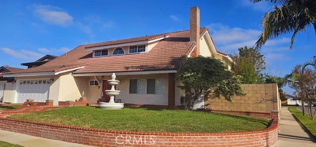 9715 Raven Cir, Fountain Valley, CA 92708 - mediterranean / spanish-style house featuring stucco siding, a front lawn, an attached garage, a tile roof, and a chimney