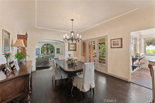 3492 Circle Rd, San Bernardino, CA 92405 - dining space featuring arched walkways, a chandelier, dark wood-style flooring, a tray ceiling, and baseboards