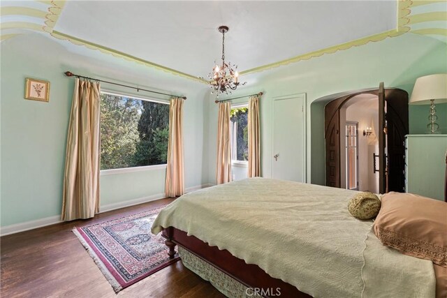 3492 Circle Rd, San Bernardino, CA 92405 - bedroom featuring arched walkways, a chandelier, wood finished floors, and baseboards