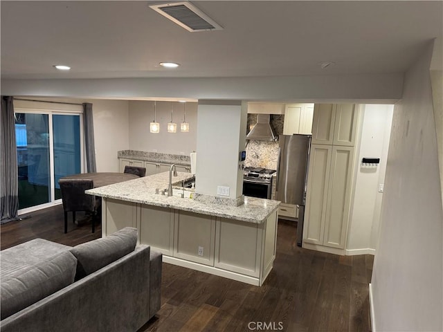 30724 Calle Resplendor, San Juan Capistrano, CA 92675 - kitchen featuring wall chimney exhaust hood, appliances with stainless steel finishes, a sink, light stone counters, and dark wood finished floors