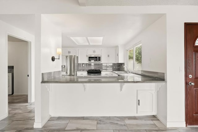 1295 Buenos Ave, San Diego, CA 92110 - kitchen with appliances with stainless steel finishes, a peninsula, white cabinetry, a breakfast bar area, and a sink