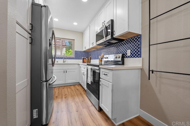 1810 Stanton Rd, Encinitas, CA 92024 - kitchen featuring appliances with stainless steel finishes, light wood-style flooring, tasteful backsplash, white cabinets, and light countertops