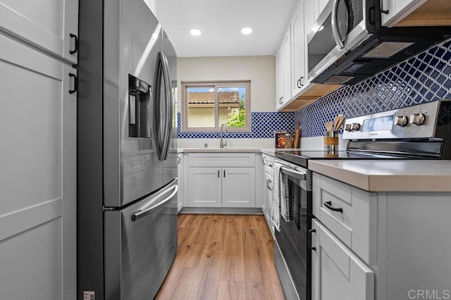 1810 Stanton Rd, Encinitas, CA 92024 - kitchen with appliances with stainless steel finishes, backsplash, white cabinetry, light wood-style flooring, and light countertops