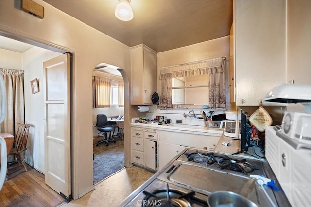 1316 Walnut St, San Gabriel, CA 91776 - kitchen with ventilation hood, arched walkways, white cabinetry, a desk, and a sink