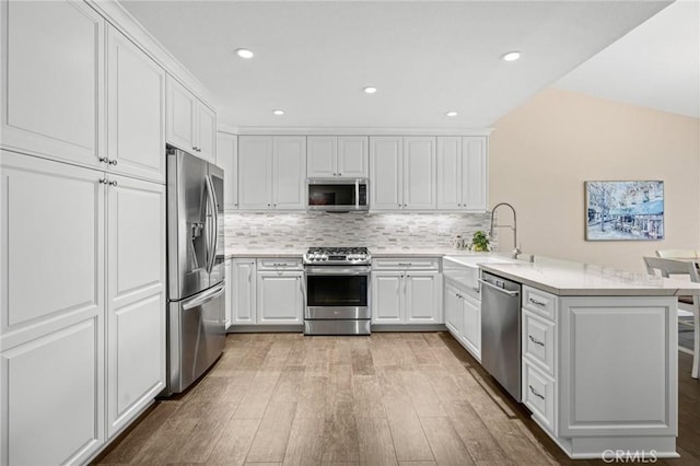 23291 Via Gaudix, Mission Viejo, CA 92691 - kitchen with stainless steel appliances, a peninsula, a sink, light wood-type flooring, and white cabinets