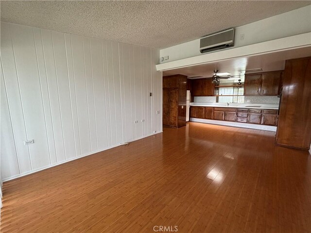 13800M1-39K Annandale Dr, Seal Beach, CA 90720 - unfurnished living room with a textured ceiling, dark wood-style floors, and a wall mounted AC