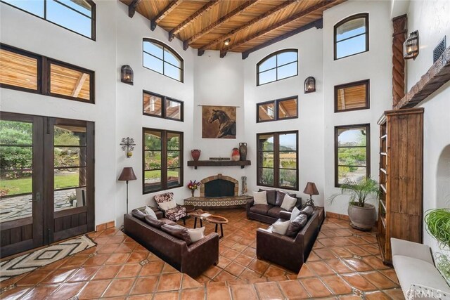 4950 Davenport Creek Rd, San Luis Obispo, CA 93401 - tiled living area with a high ceiling, a wood ceiling with exposed beams, a fireplace with raised hearth, and french doors