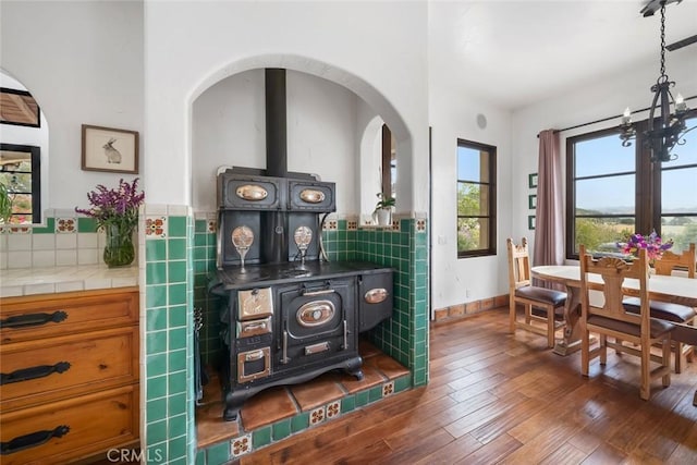 4950 Davenport Creek Rd, San Luis Obispo, CA 93401 - dining area featuring a wood stove, wood finished floors, a chandelier, and arched walkways
