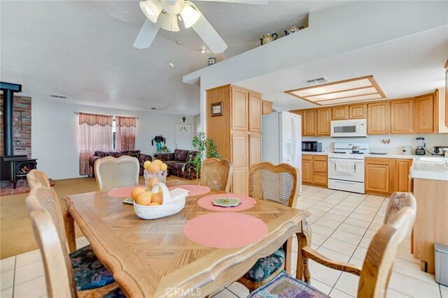21919 Standing Rock Ave, Apple Valley, CA 92307 - dining space featuring light tile patterned floors, a wood stove, vaulted ceiling, and a ceiling fan
