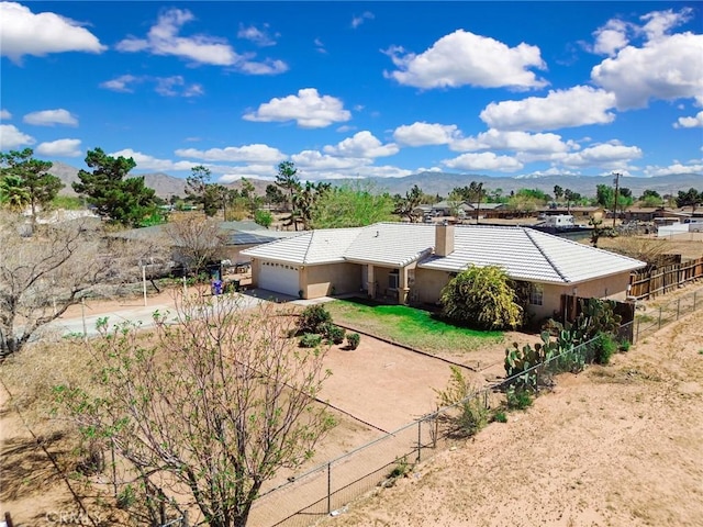 21919 Standing Rock Ave, Apple Valley, CA 92307 - back of house with dirt driveway, an attached garage, a tiled roof, a mountain view, and a chimney