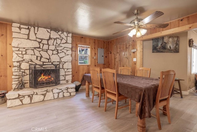 745 Sunset Ln, Sugarloaf, CA 92386 - dining space with wooden walls, electric panel, a stone fireplace, a ceiling fan, and wood finished floors
