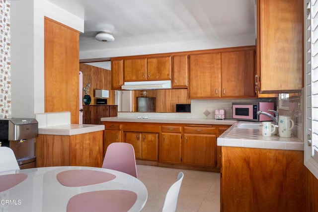 85 Gardenia Ct, Upland, CA 91786 - kitchen featuring brown cabinets, a sink, tasteful backsplash, tile countertops, and white microwave