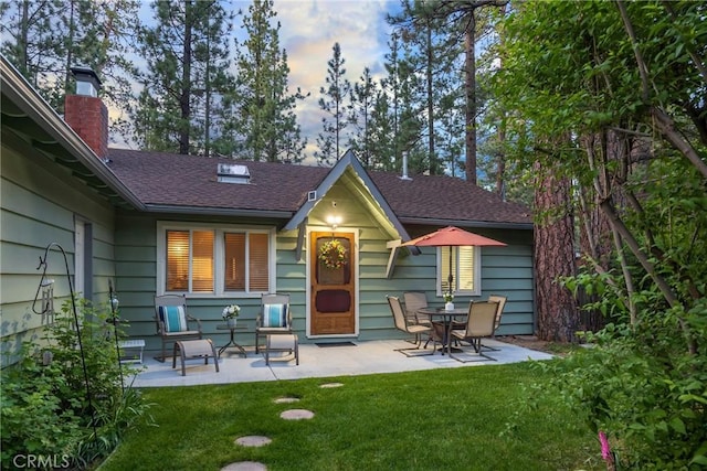 913 W Rainbow Blvd, Big Bear City, CA 92314 - back of house with a patio area, a lawn, a shingled roof, and a chimney