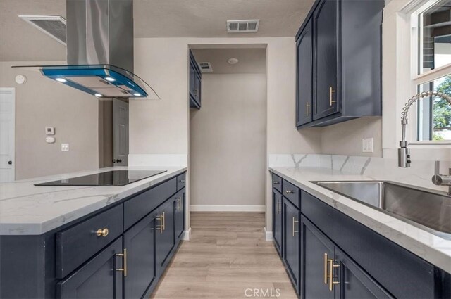 1906 N Fruit Ave, Fresno, CA 93705 - kitchen with island exhaust hood, black electric cooktop, a sink, light wood-style flooring, and light stone counters