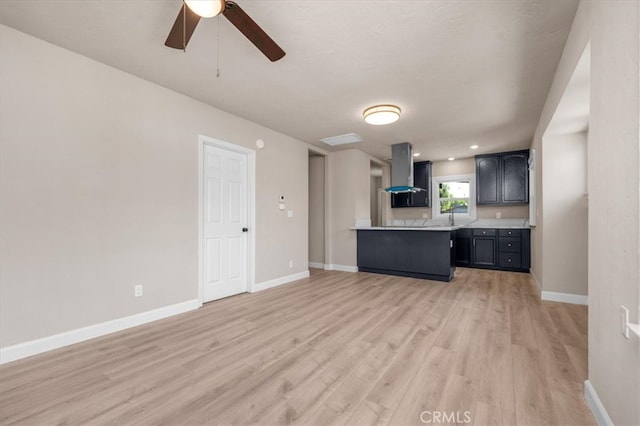 1906 N Fruit Ave, Fresno, CA 93705 - kitchen with wall chimney exhaust hood, light countertops, light wood-style flooring, ceiling fan, and baseboards