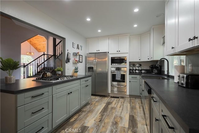 1315 Sequoia Dr, Lake Arrowhead, CA 92352 - kitchen with stainless steel appliances, dark countertops, a sink, a warming drawer, and light wood-style floors