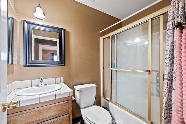 8600 San Vicente Dr, Yucca Valley, CA 92284 - bathroom featuring vanity, combined bath / shower with glass door, toilet, and a textured wall