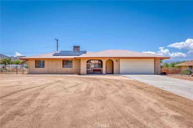 8600 San Vicente Dr, Yucca Valley, CA 92284 - single story home with driveway, a garage, roof mounted solar panels, and stucco siding