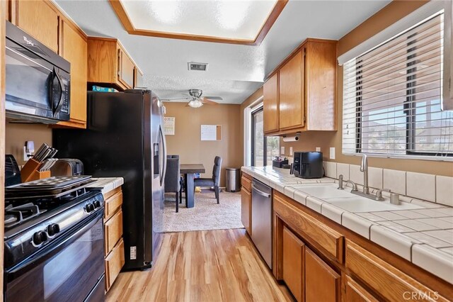 8600 San Vicente Dr, Yucca Valley, CA 92284 - kitchen featuring stainless steel appliances, ceiling fan, tile counters, light wood finished floors, and a sink