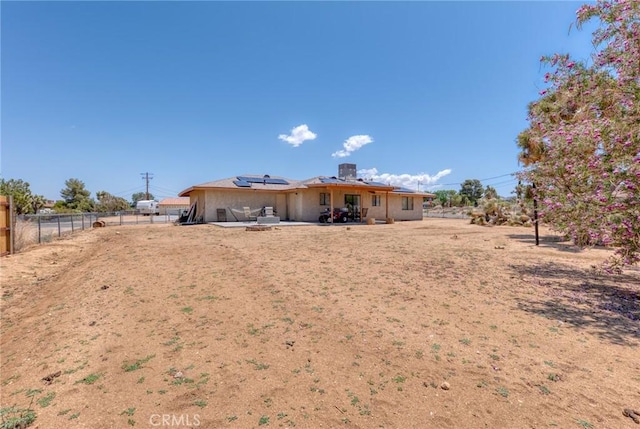 8600 San Vicente Dr, Yucca Valley, CA 92284 - rear view of property featuring roof mounted solar panels, a patio area, a fenced backyard, and stucco siding