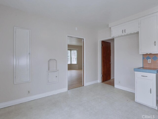 4265 Crescent Ave, Cypress, CA 90630 - kitchen with light flooring, backsplash, baseboards, and white cabinetry